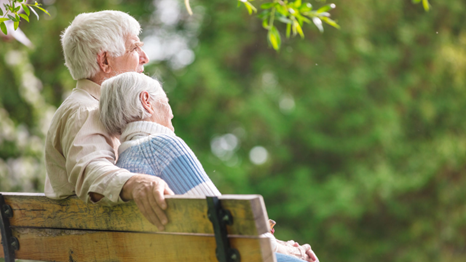 Stock photo of an older couple leaning into each other on a a park bench